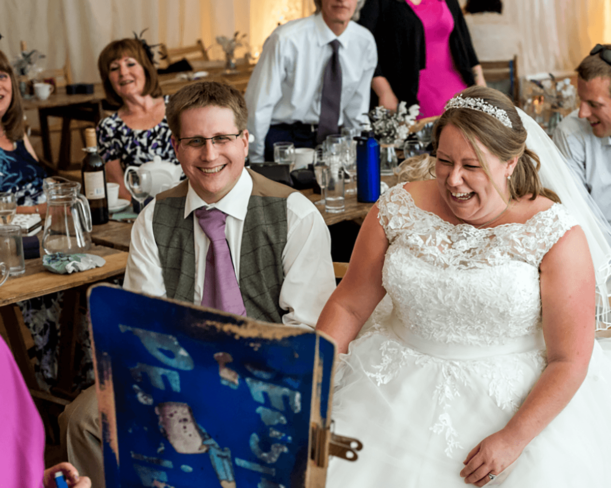 Bride and groom laughing as they see their caricature drawing at their wedding