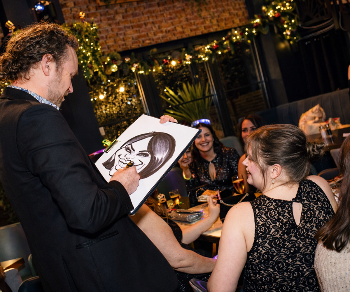 christmas-party-caricatures Guests laughing with caricature portraits at Christmas party event