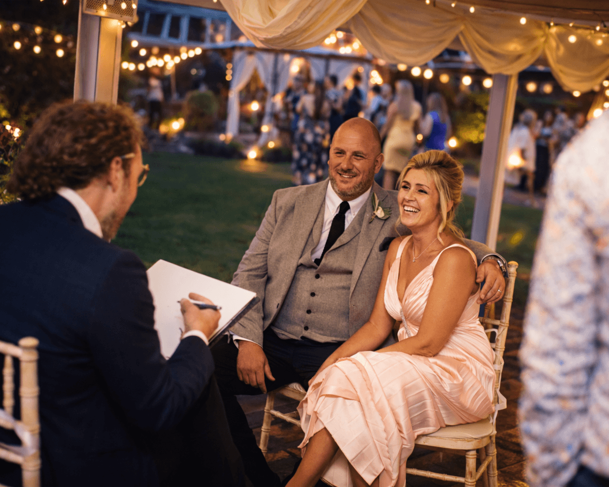Wedding caricature artist drawing a bride and groom during an evening wedding reception